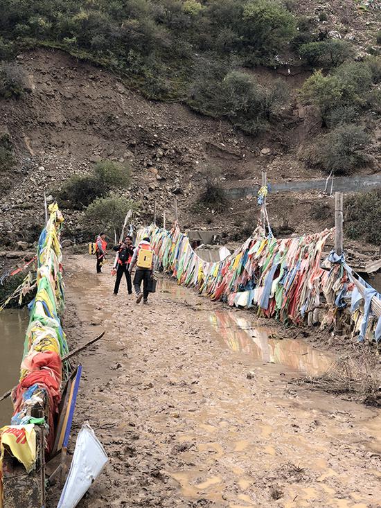 監(jiān)測(cè)人員踩著泥濘道路轉(zhuǎn)移觀測(cè)點(diǎn)。昌都市水文局圖