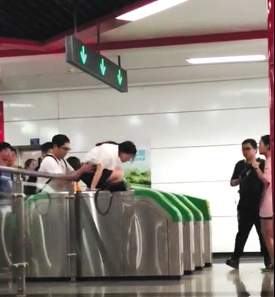 爬 一女子在男同伴的“扶助”下，爬過地鐵檢票閘機口。視頻截圖