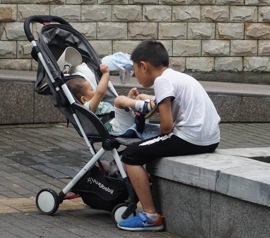 小哥哥看弟弟很有耐心，即使小腳踢到身上也不惱。笑槑/攝