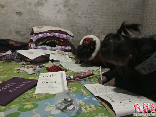 1月4日，張歡張圓姐妹正趴在床上寫作業。中國青年報·中青在線記者?孫慶玲/攝