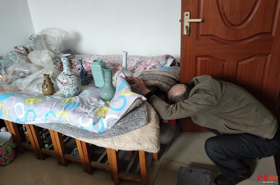 徐大爺從床底下將購買的假古董拿到床上