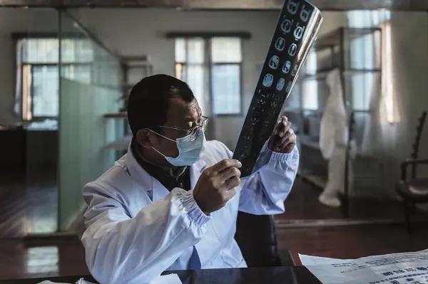 3月7日，硚口區六角亭街道社區衛生服務中心主任羅浩在一間臨時的辦公場所對著窗戶看CT片。